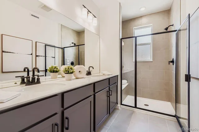 a bathroom with a double vanity sink mirror and shower