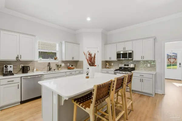 a kitchen with stainless steel appliances a sink a stove a refrigerator cabinets and a center island