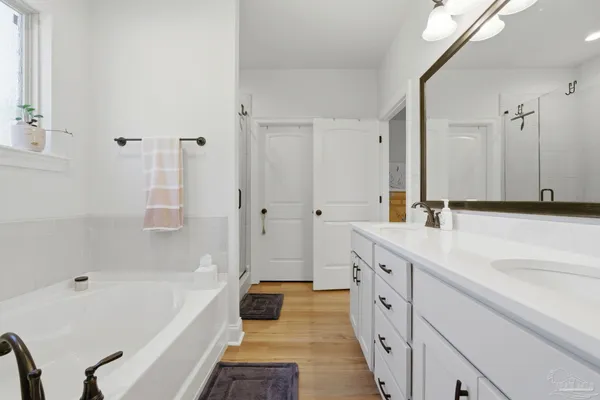 a spacious bathroom with a tub sink and mirror