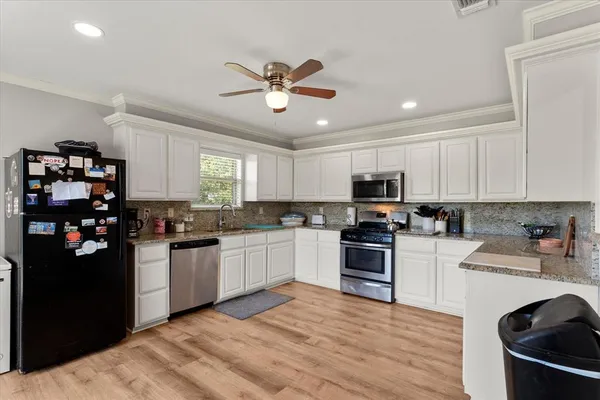 a kitchen with stainless steel appliances granite countertop a refrigerator stove top oven and sink