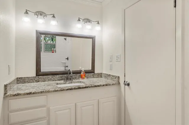a bathroom with a granite countertop sink and a mirror