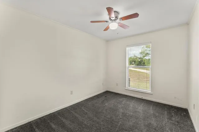 an empty room with a window and a ceiling fan