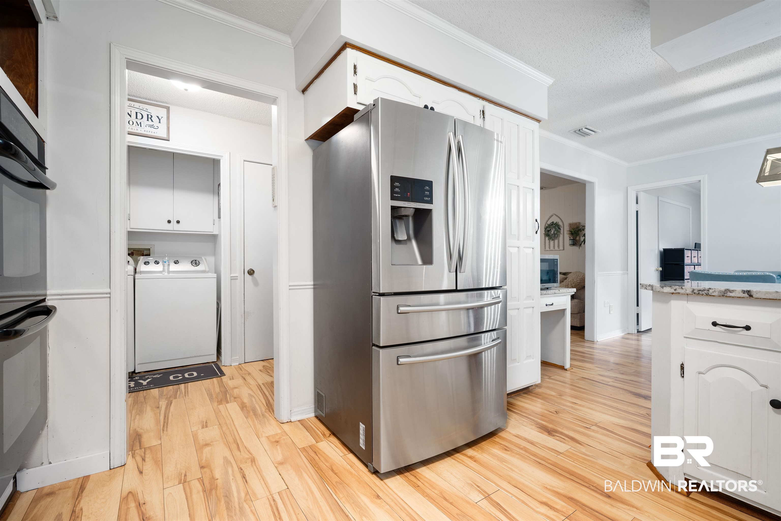 7807 Yorkhaven Road Mobile, AL 36695 - Photo 9 of 34 Kitchen featuring stainless steel fridge, white cabinets, ornamental molding, double oven, and light wood finished floors