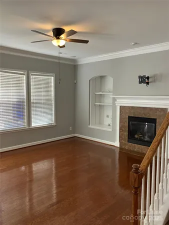 a view of an empty room with wooden floor fireplace and a window
