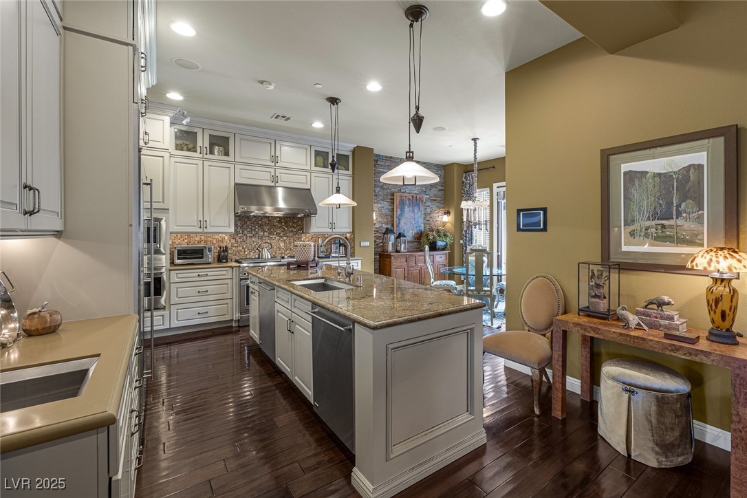 11280 Granite Ridge Drive, Unit 1057 Las Vegas, NV 89135 - Photo 11 of 46 Kitchen featuring glass insert cabinets, tasteful backsplash, pendant lighting, recessed lighting, and a kitchen island with sink