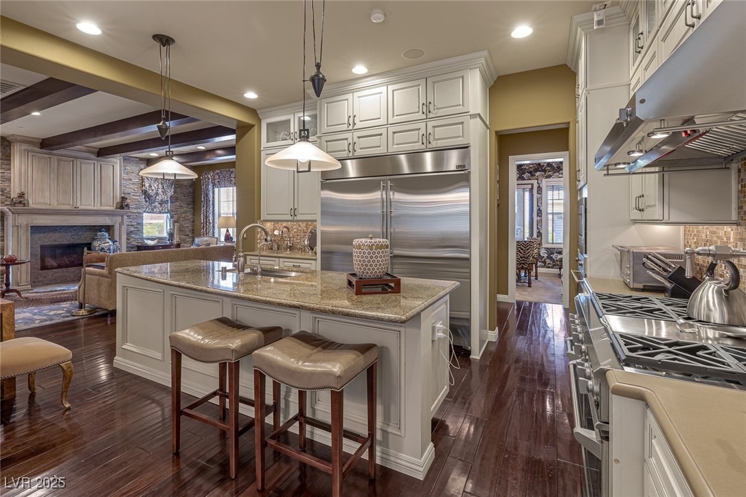11280 Granite Ridge Drive, Unit 1057 Las Vegas, NV 89135 - Photo 15 of 46 Kitchen with under cabinet range hood, backsplash, appliances with stainless steel finishes, a breakfast bar, and decorative light fixtures