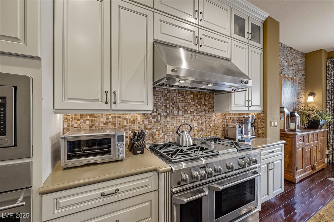 11280 Granite Ridge Drive, Unit 1057 Las Vegas, NV 89135 - Photo 18 of 46 Kitchen with stainless steel appliances, under cabinet range hood, light countertops, decorative backsplash, and white cabinets