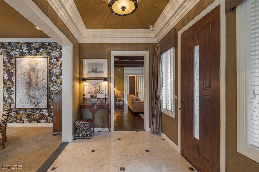 11280 Granite Ridge Drive, Unit 1057 Las Vegas, NV 89135 - Photo 3 of 46 Tiled foyer with inlaid floor details, a tray ceiling, ornamental molding, and wallpapered walls
