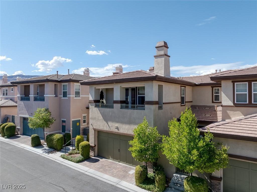 11280 Granite Ridge Drive, Unit 1057 Las Vegas, NV 89135 - Photo 33 of 46 View of front of property featuring stucco siding, decorative driveway, an attached garage, and a chimney