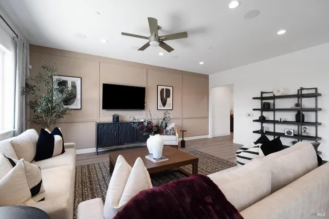 a living room with furniture a ceiling fan and a flat screen tv