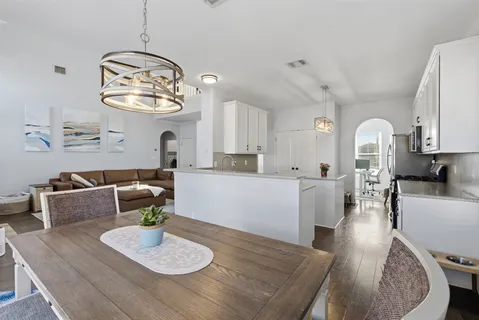 a living room with furniture kitchen view and a chandelier