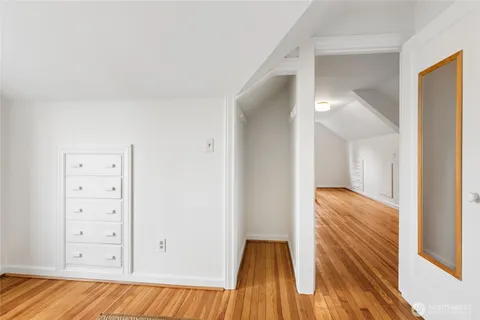 a view of a hallway with wooden floor and a bathroom