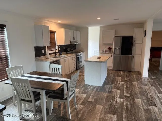 a kitchen with a table chairs refrigerator and microwave