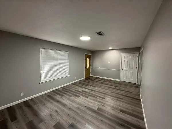 a view of an empty room with wooden floor and a window