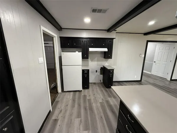 a kitchen with a refrigerator and white cabinets