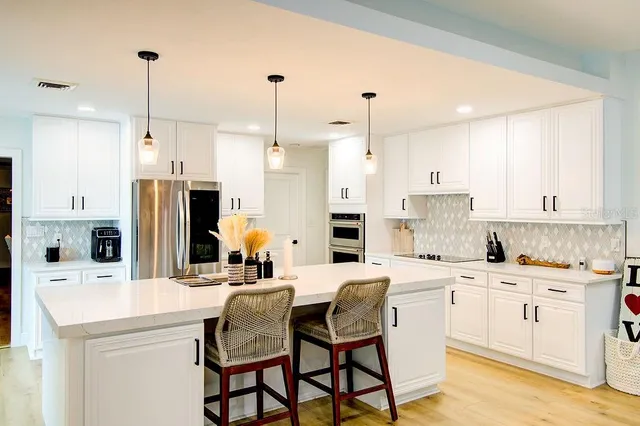 a kitchen with stainless steel appliances kitchen island granite countertop a sink a stove a refrigerator and cabinets