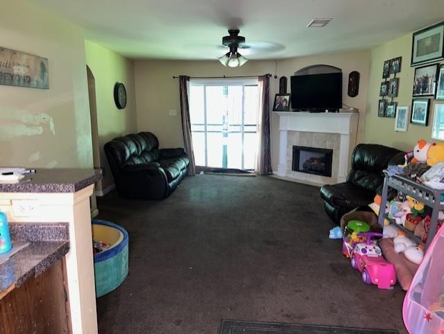 3784 McCain Road Memphis, TN 38109 - Photo 6 of 14 Living area featuring a corner fireplace with a white mantel and tile surround, sliding glass door access to an exterior space, an arched doorway, and an overhead ceiling fan