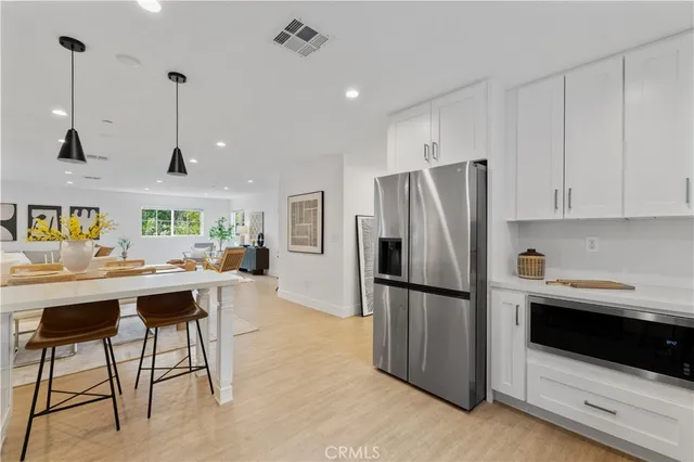 a kitchen with stainless steel appliances kitchen island a table chairs in it and wooden floors