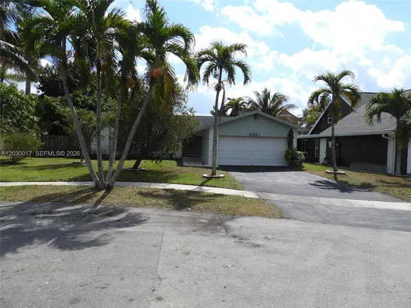 a view of a house with a yard and palm trees