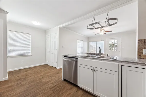 a kitchen with a sink dishwasher a stove and white cabinets with wooden floor