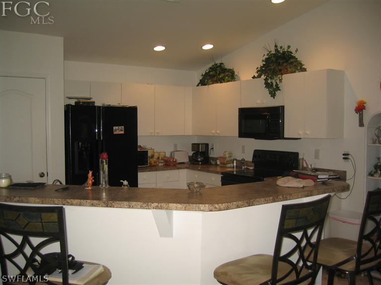3618 20th Street Southwest Lehigh Acres, FL 33976 - Photo 4 of 12 a kitchen with granite countertop a refrigerator and a stove top oven