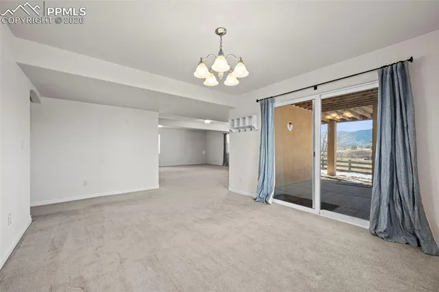 an empty room with chandelier fan and windows