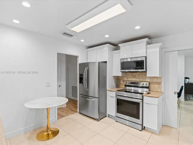 a kitchen with stainless steel appliances a refrigerator a stove a microwave oven and a sink