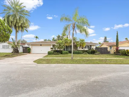 a view of a house with a yard and palm trees