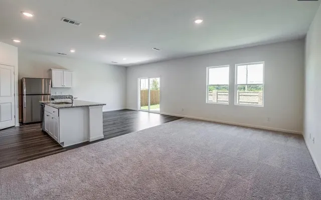 an empty room with windows and kitchen view