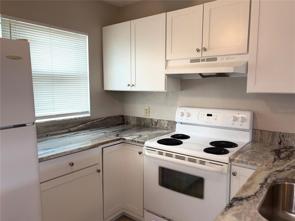26485 Rampart Boulevard, Unit D1 Punta Gorda, FL 33983 - Photo 4 of 29 a kitchen with granite countertop white cabinets and white appliances