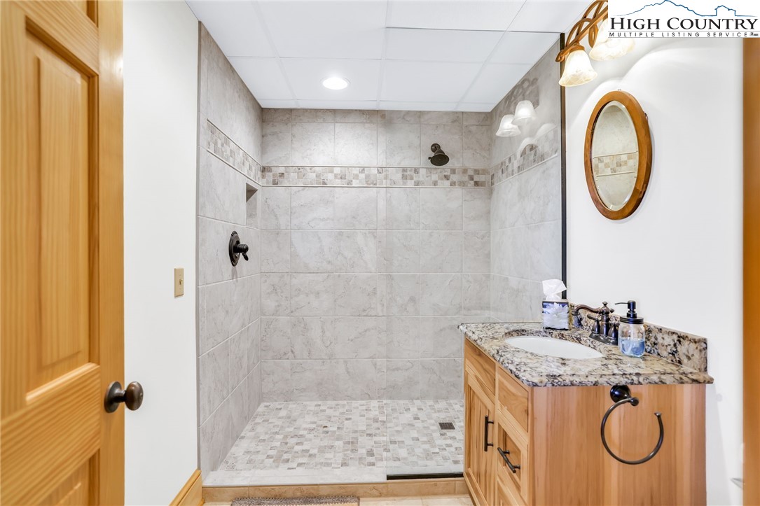 324 Rocky Ridge Lane Glade Valley, NC 28627 - Photo 36 of 43 a bathroom with a granite countertop sink a mirror and a shower
