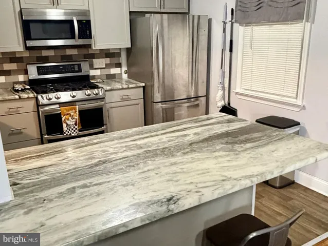 a kitchen with kitchen island granite countertop a stove and a refrigerator