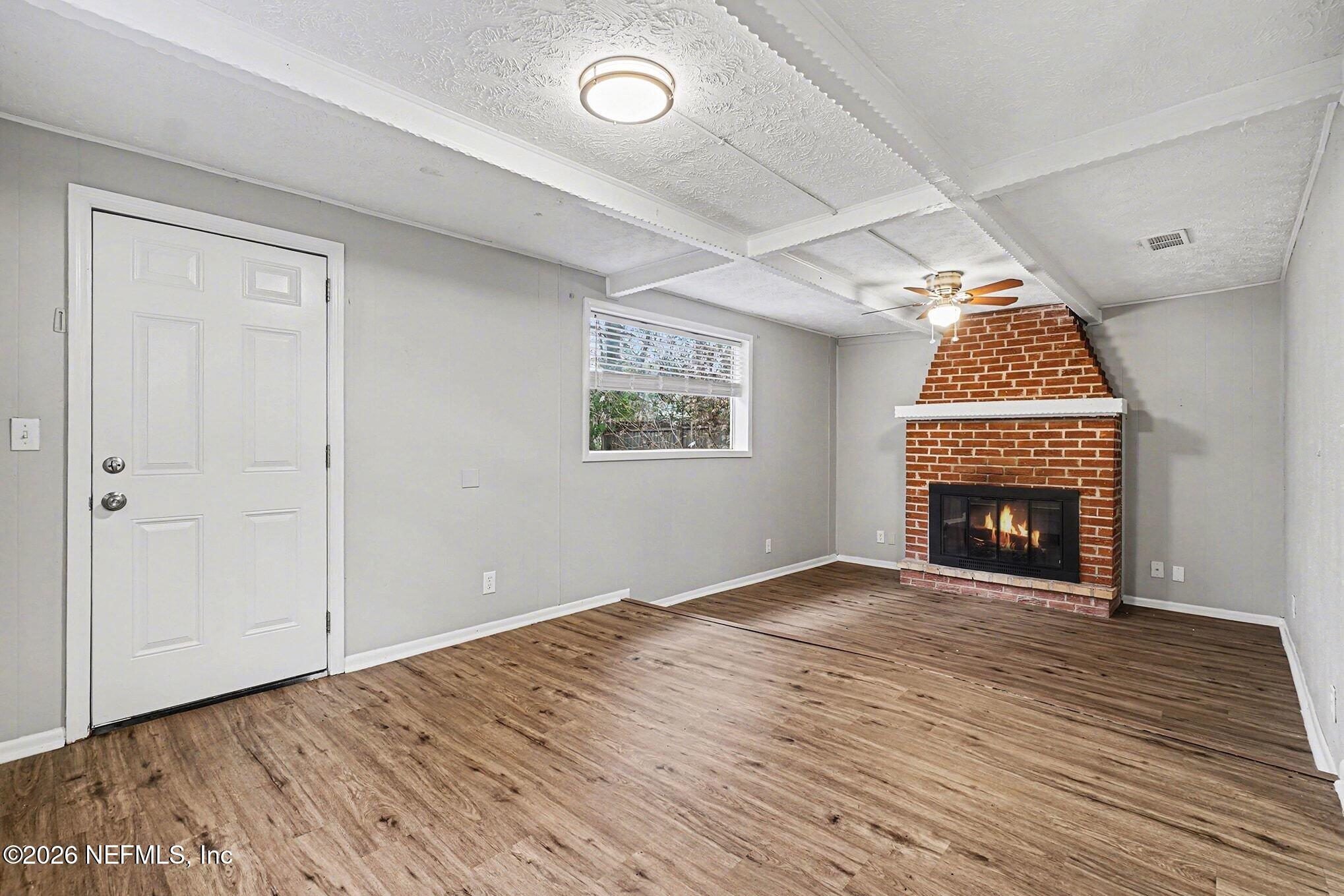 8417 Barracuda Road Jacksonville, FL 32244 - Photo 2 of 15 an empty room with wooden floor a fireplace and windows