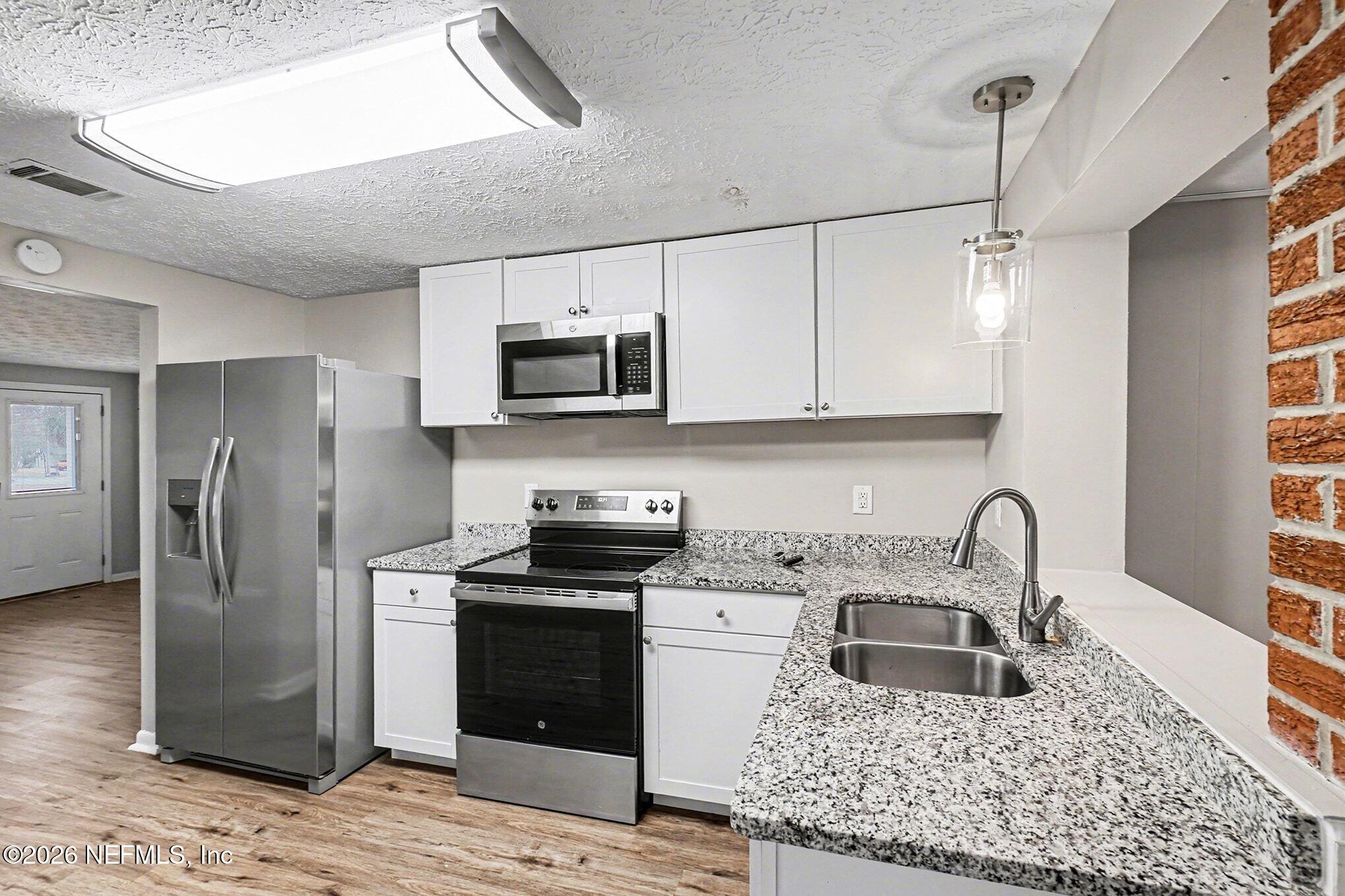 8417 Barracuda Road Jacksonville, FL 32244 - Photo 6 of 15 a kitchen with stainless steel appliances granite countertop a sink stove microwave and refrigerator
