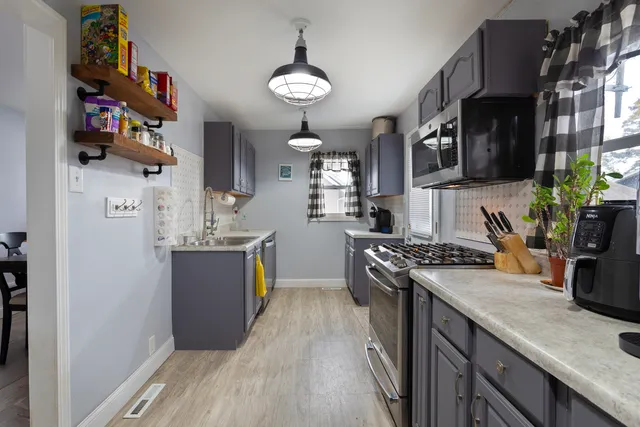 a kitchen with stainless steel appliances granite countertop a stove a sink dishwasher and a refrigerator with wooden floor