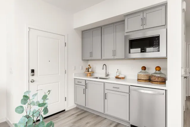 a kitchen with stainless steel appliances white cabinets and wooden floor
