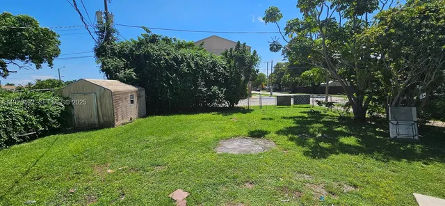 a backyard of a house with table and chairs plants and large tree
