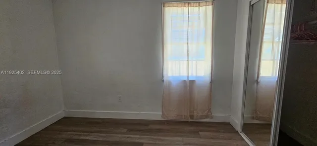 a view of an empty room with wooden floor and closet