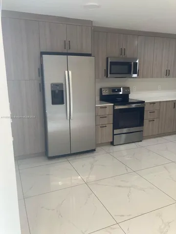 a kitchen with granite countertop a refrigerator and a stove top oven