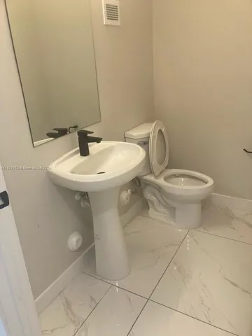 a bathroom with a toilet a sink and mirror