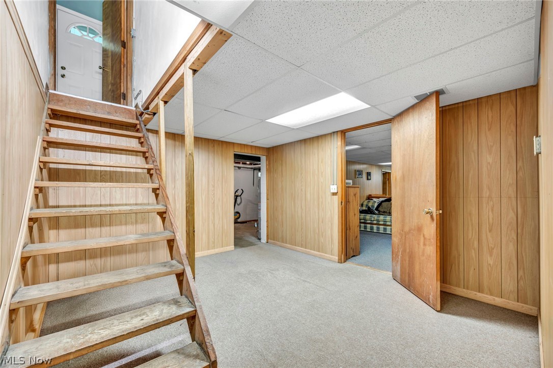 1927 Connect Road Barberton, OH 44203 - Photo 22 of 28 Stairs with a paneled ceiling, light carpet, and wooden walls