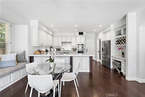 a kitchen with stainless steel appliances kitchen island granite countertop a table chairs stove and white cabinets