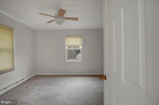an empty room with a window and a ceiling fan