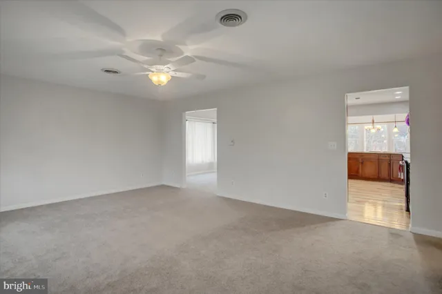 an empty room with chandelier fan and windows