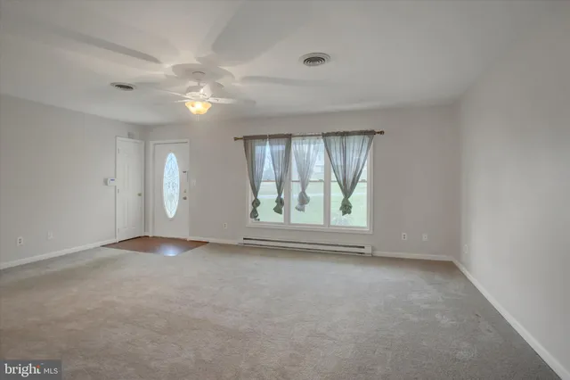 an empty room with chandelier fan and windows
