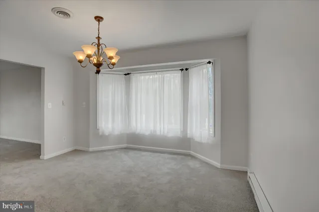 an empty room with a chandelier fan and window