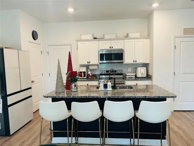 a kitchen with stainless steel appliances granite countertop a dining table chairs and white cabinets