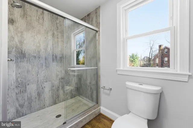 a bathroom with a granite countertop sink toilet mirror and shower