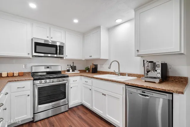 a kitchen with granite countertop a stove a sink and a microwave