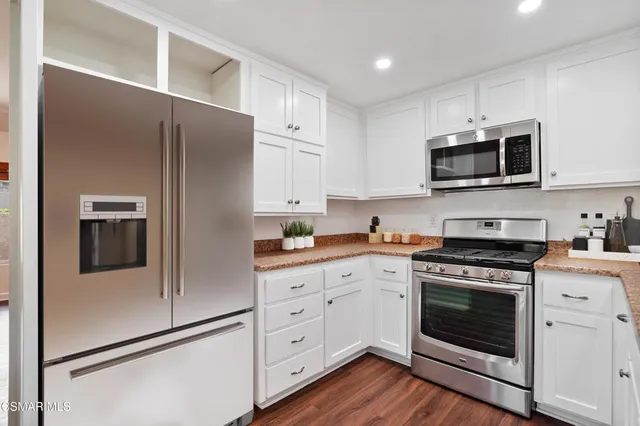 a kitchen with stainless steel appliances white cabinets white stove and a refrigerator